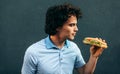Side view image of young handsome man eating a healthy burger. Hungry man in a fast food restaurant eating a hamburger outdoors. Royalty Free Stock Photo