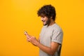 Side view at Indian man with curly hair using cellphone, typing text message Royalty Free Stock Photo