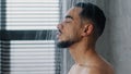 Side view indian relaxed man bearded guy naked male washes head hair face and beard in bathroom showering in at home in