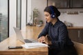 Side view Indian woman wearing headphones looking at laptop screen Royalty Free Stock Photo