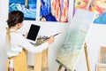 side view of kid looking at tablet and painting on canvas in workshop of Royalty Free Stock Photo