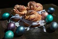 Side view of kraffins on a napkin and Easter eggs on a wooden background, with ribbons and icing sugar Royalty Free Stock Photo