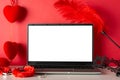 Side view laptop with blank screen, mask, sensual accessories like furry handcuffs, feather tickler vivid red backdrop