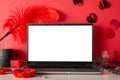 Side view of laptop, candles, mask, and adult toys furry handcuffs and feather tickler on red background