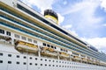 Side view of a large cruise ship with many hanging lifeboats and liferafts, blue sky background Royalty Free Stock Photo