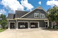 The side view of a large gray craftsman new construction house with a landscaped yard a three car garage and driveway Royalty Free Stock Photo