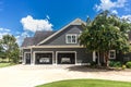 The side view of a large gray craftsman new construction house with a landscaped yard a three car garage and driveway Royalty Free Stock Photo