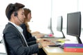 Side view of line of call centre employees are smiling and working on computers. Businesspeople In A Row Wearing Headset Working Royalty Free Stock Photo