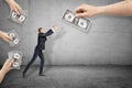 Side view of little businessman reaching out for one of dollar bills given to him by big hands all around. Royalty Free Stock Photo