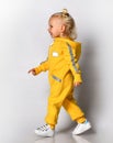 Side view of a little girl in a blue warm jumpsuit walking along the wall. Royalty Free Stock Photo