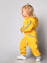 Side view of a little girl in a blue warm jumpsuit walking along the wall. Royalty Free Stock Photo