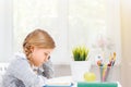 Side view of a little student girl sitting at a table reading a book. The concept of education and school. Royalty Free Stock Photo