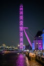 Side view of The London Eye colourfully illuminated at night