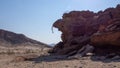 Side view of a lone stone man hanging from the rock above a shallow cave. The lone men are a mystery found in the northern