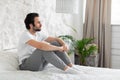 Side view of lonely young man sitting on bed alone Royalty Free Stock Photo