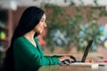 Side view of long-haired brunette woman using laptop, cafe interior Royalty Free Stock Photo