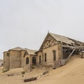 Side view with lot of sand to the Lehrer house at German Kolmanskop Ghost Town with the abandoned buildings