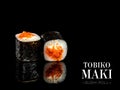 Side view of Maki sushi roll pieces with mirror reflection on black background. Sushi roll with flying fish roe Tobiko, cream Royalty Free Stock Photo