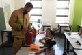 Side view of male Caucasian firefighter teaching schoolkids about fire safety in classroom