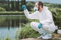 side view of male scientist in protective suit examining sample of water in test flask Royalty Free Stock Photo