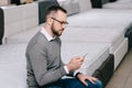 side view of male shopper with smartphone sitting on mattress