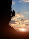 Male silhouette climbing on rock at sunrise. Adrenaline, strength, ambition. Side low angle view. Filtered. Copy space