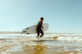 Side view of male surfer in wetsuit with his surfboard entering the sea. Surfing on ocean Royalty Free Stock Photo