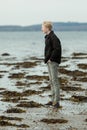 Side view of male teen in jeans on beach