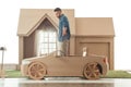 side view of man in cardboard car in front of cardboard house Royalty Free Stock Photo