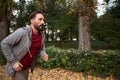 Side view of man running in autumn forest.