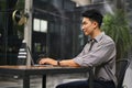Side view of a man is using his laptop and sitting at a coffee shop in an outdoor space Royalty Free Stock Photo