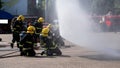 A side view of many firefighters is practicing using