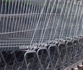 Side view of many metal shopping carts standing in a row on the street