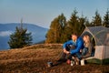 Pair having rest in campsite in mountains at sunny autumn.