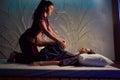 Focused massage therapist stretching lower extremities of female patient