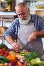 Side view of mature man slicing cucumber on cutting board Royalty Free Stock Photo