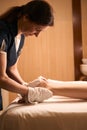 Focused massotherapist prepping customer for leg massage