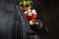 Side view on mini party tartlets with fresh fruit, chocolate, nuts and cream on black slate background