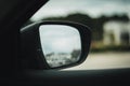 Side view mirror of a car, revealing the side and driver of the vehicle