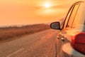 Side view mirror of car on road in autumn sunset