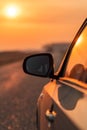 Side view mirror of car on road in autumn sunset Royalty Free Stock Photo