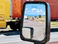 side view mirror on front of car showing trucks in the back Royalty Free Stock Photo