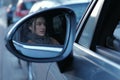 Side view mirror portrait of an attractive woman driving a car in a traffic Royalty Free Stock Photo