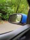 Side view mirror reflection of two-lane winding road in forest, beautiful green nature Royalty Free Stock Photo