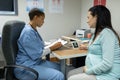 Female doctor giving prescription to pregnant woman at desk in hospital Royalty Free Stock Photo