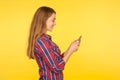Side view of mobile customer smiling, happy girl in shirt typing message on smartphone, looking satisfied pleased with app