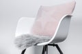 Side view of a modern white plastic chair with a light rosa pillow and a seat cushion made of grey artificial long fur, use as Royalty Free Stock Photo