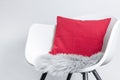 Side view of a modern white plastic chair with a pink pillow and a seat cushion made of grey artificial long fur, use as design Royalty Free Stock Photo