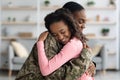 Side view of mom in military uniform hugging child