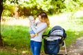 Side view of mother holding baby standing near stroller Royalty Free Stock Photo